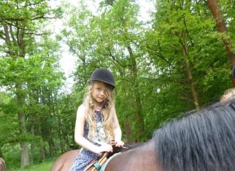 Auf dem Bild ist ein Mädchen auf dem Pferd zu sehen