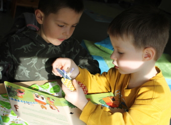 Zwei Kindergartenkinder beschäftigen sich mit einem Spielbuch