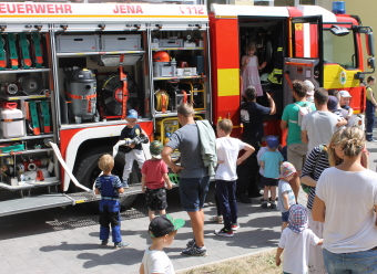 Auf dem Bild sind Kinder zu sehen, die an einem Feuerwehrfahrzeug spielen