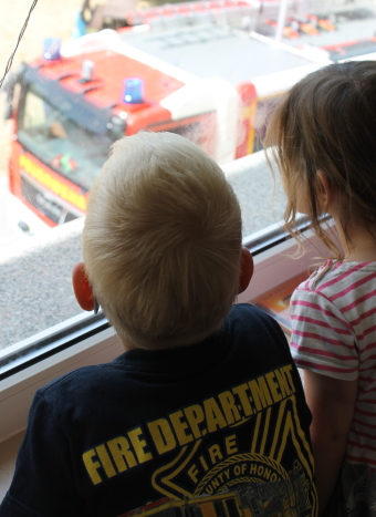 Auf dem Bild sind zwei Kinder am Fenster zu sehen