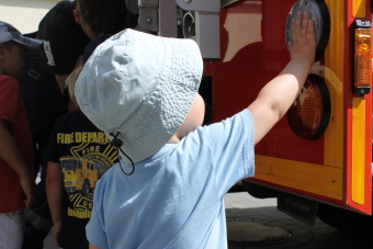 Auf dem Bild ist ein Kind zu sehen, das das Feuerwehrauto anfasst
