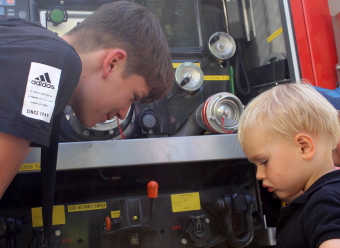 Auf dem Bild sind zwei Kinder vor einem Feuerwehrauto zu sehen