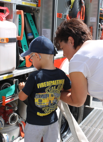 Auf dem Bild ist eine Frau mit einem Kind neben einem Feuerwehrauto zu sehen