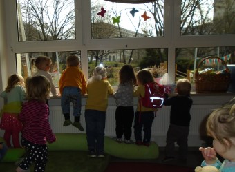 Mehrere kleine Kinder schauen aus dem Fenster in den Garten